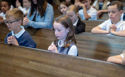 Children praying during Mass at a Catholic church.